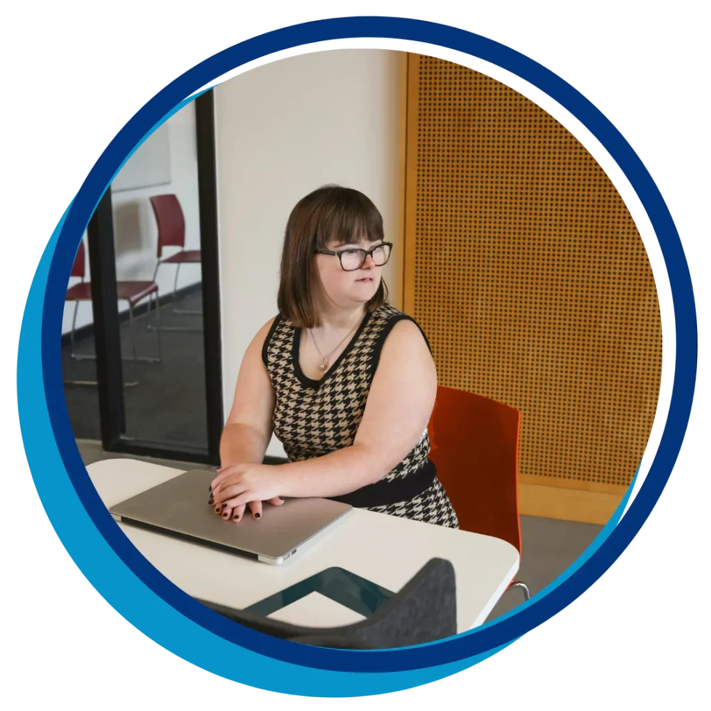 A woman with down syndrome is sitting in a library