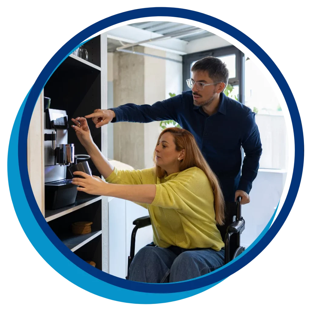 A woman in a wheelchair is being helped by a support worker with a coffee machine