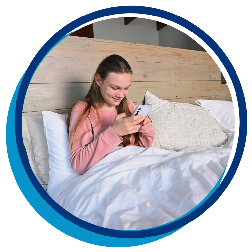 A young woman with a disability is sitting in bed while on her phone