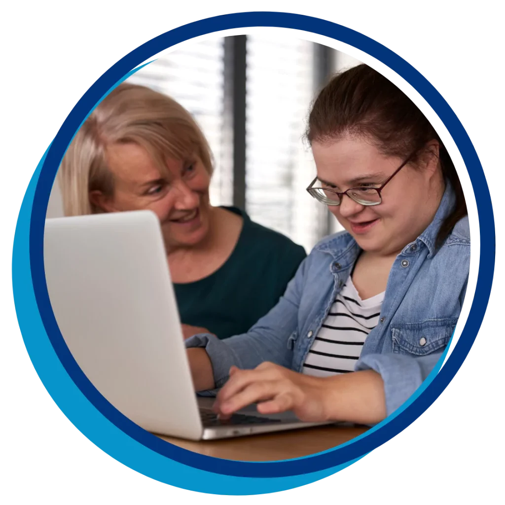 A young woman with down syndrome is smiling while using her laptop