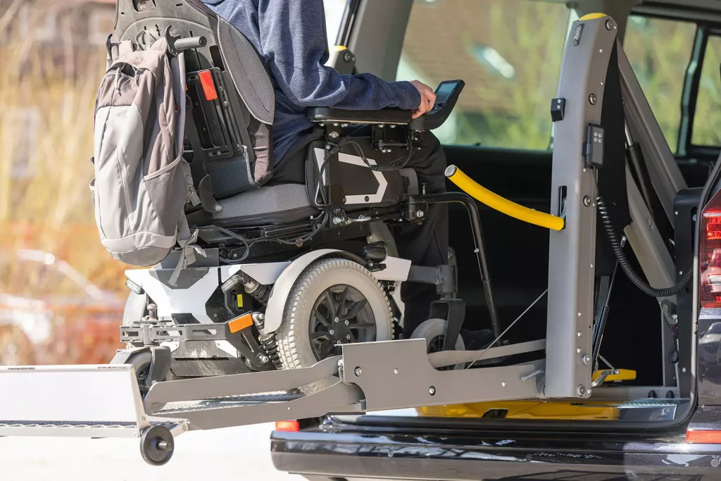 A specialty wheelchair is being hoisted into the back of a van