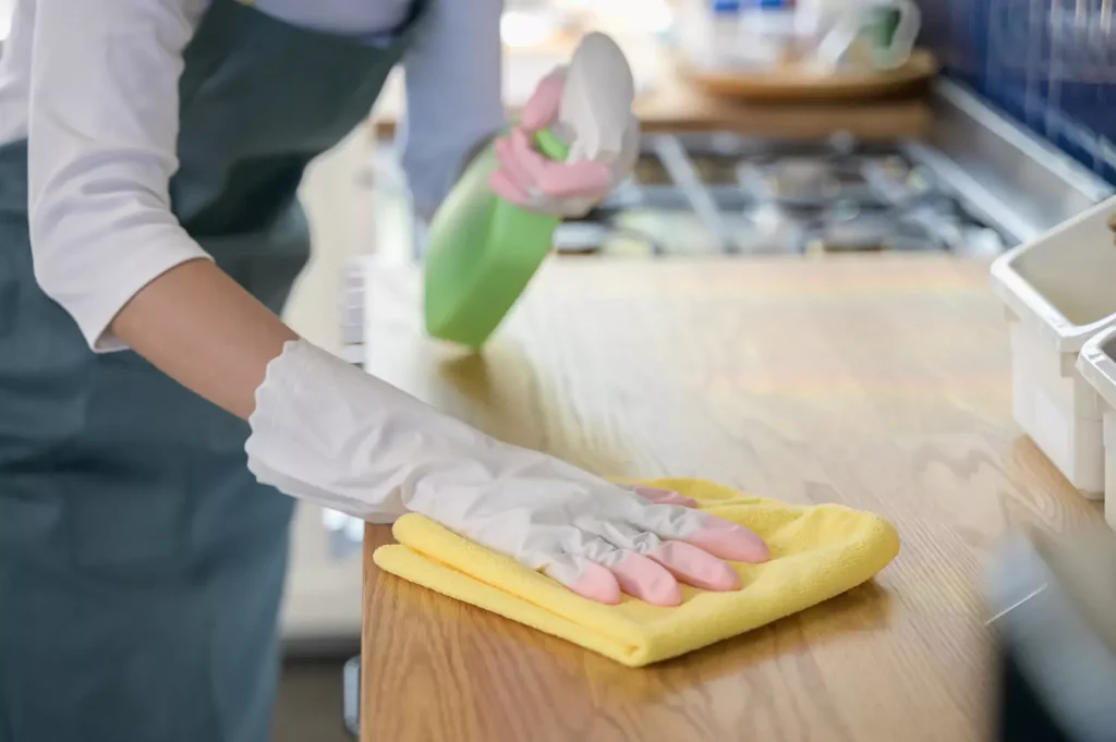 A woman is cleaning a kitchen bench